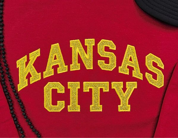 Sudadera de cuello redondo en rojo oscuro con apliques de purpurina dorada de Kansas City